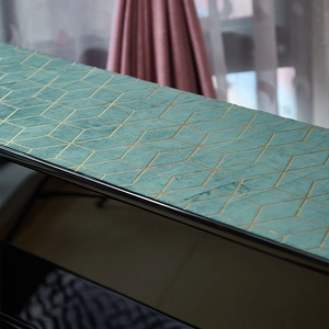 Close-up of teal velvet piano cover with golden geometric diamond mesh pattern