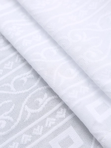 Detailed close-up of white jacquard fabric with elegant floral and geometric patterns