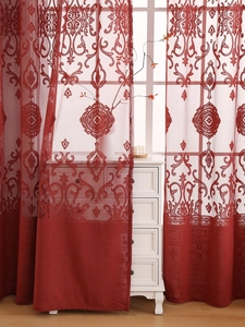 Detail of red embroidered lace curtain with classical scroll patterns and grommet top