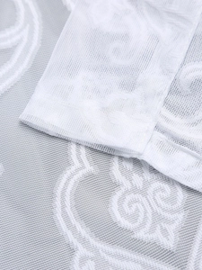 Detail of white lace mesh fabric with intricate embroidery and neat hemline stitching