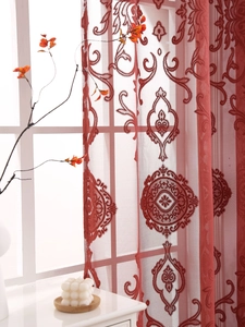 Detail of red damascus embroidered sheer curtain with intricate floral lace patterns