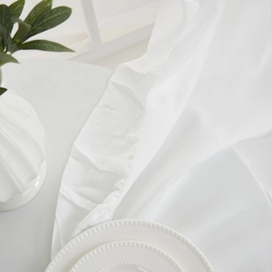 Macro detail of breathable white cotton linen fabric with refined hemmed edges on a table