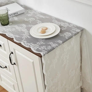 Détail du chemin de table en dentelle blanche avec broderie florale et bords ondulés