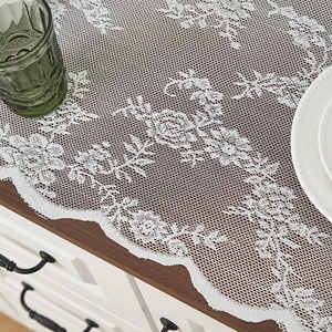 Gros plan d'une nappe en dentelle blanche aux motifs floraux sur table en bois foncé