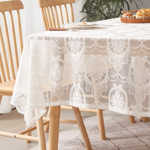 Close-up of vintage French white lace tablecloth featuring floral and bow patterns