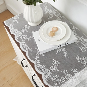 Détail du chemin de table en dentelle blanche avec motifs roses et bords ondulés