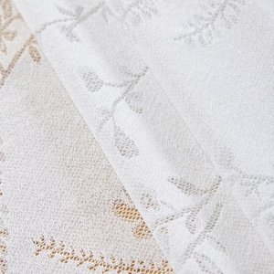Close-up of white lace tablecloth featuring intricate floral patterns and ruffled edges