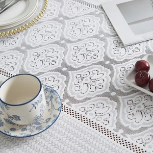 Gros plan sur nappe en dentelle blanche avec broderie florale et bords ondulés