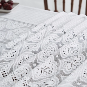 Détail de la nappe en dentelle blanche avec motifs floraux en cœur et bords ajourés