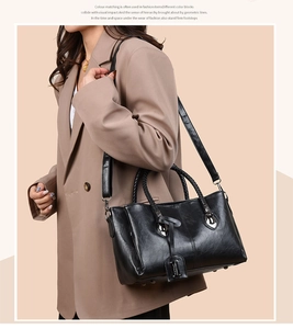 Detail of black tote bag featuring woven handle and detachable strap on casual suit