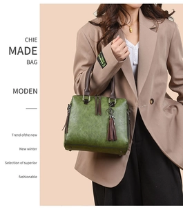 Detail view of a vintage dark green leather tote with tassel charm and brown handles