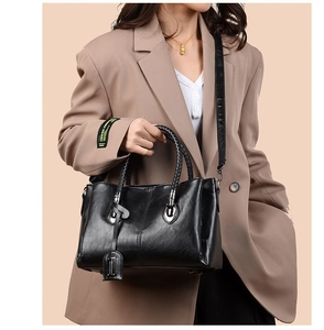 Close-up of black oil wax leather tote bag with woven handles and silver metal hardware