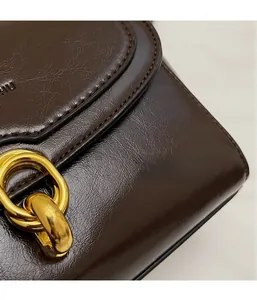 Détail du cuir ciré marron foncé et boucle métallique dorée sur le sac à main