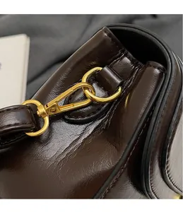 Détail du sac en cuir ciré marron foncé avec crochets dorés et coutures de précision