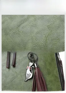 Detailed macro view of litchi texture green leather bag with cat charm and tassel