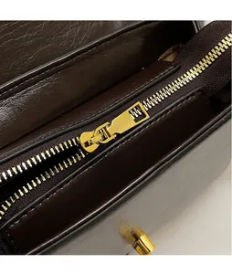 Gros plan sur la fermeture éclair dorée et les finitions de ce sac à main rétro en cuir brun