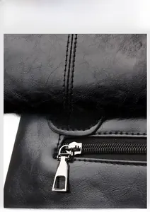Detail of high-quality black faux leather texture and silver metal zipper on a tote bag