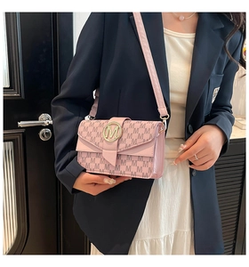 Detail of pink crossbody bag featuring M letter monogram print and golden metal buckle