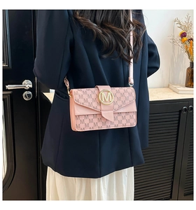 Detail of light pink crossbody bag with monogram pattern and gold M letter metal buckle