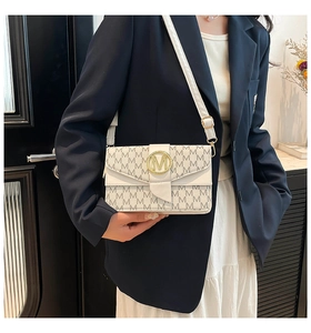Close-up of white monogram crossbody bag with golden M logo buckle on model