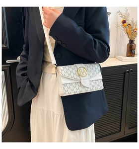Detail shot of white shoulder bag featuring grey M logo prints and golden metal buckle