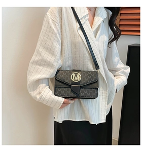 Detail of vintage monogram crossbody bag with metallic M-shaped buckle and gold hardware