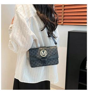 Detail of black baguette bag featuring monogram M print and gold metal buckle on flap