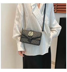 Detail of vintage black flap bag showing gold M buckle and monogram texture