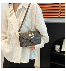 Detailed view of brown leather bag with M letter pattern and golden metal logo