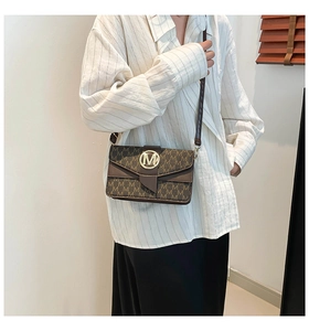 Close-up of brown crossbody bag with gold M logo and elegant letter print texture