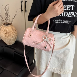 Pink snakeskin pattern pillow bag with pearl bow and heart charm on a leather sofa