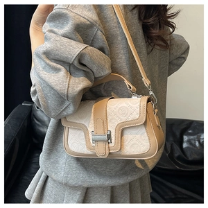 Vista indossata di una borsa a tracolla beige con motivi a rilievo e fibbia argentata
