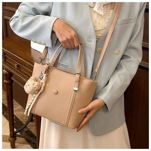 Sac cabas beige grainé avec breloque ours et foulard en soie porté par un mannequin