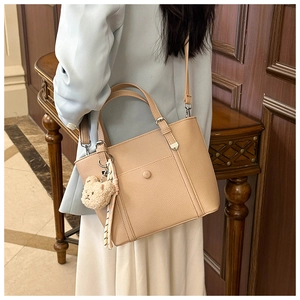 Détail du sac cabas en similicuir beige à texture litchi et breloque ourson