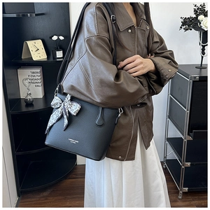 Détail du sac seau noir en cuir grainé avec foulard en soie et logo blanc imprimé