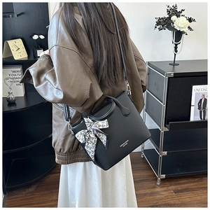 Détail d'un sac seau noir en cuir grainé avec foulard en soie à cœurs et lettres dorées