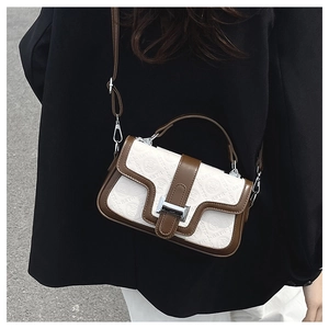 Modella che indossa una borsa a tracolla crema goffrata con finiture marroni e chiusura in metallo