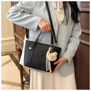 Détail du sac à main en cuir grainé noir avec bandoulière et pendentif ours mignon