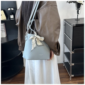 Détail du sac seau bleu clair avec texture grainée et poignée en foulard à cœurs