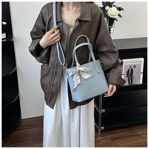 Détail du sac seau bleu clair avec texture cuir grainé et foulard en soie à cœurs