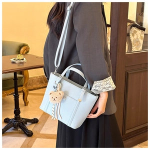 Sac à main bleu clair en cuir grainé avec un pendentif ours en peluche et bandoulière