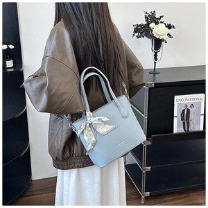 Détail du sac cabas en cuir bleu clair avec foulard décoratif en soie sur l'anse