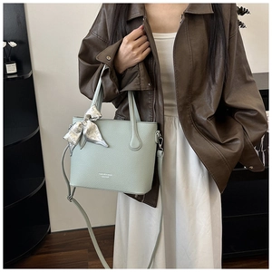 Détail du sac seau vert menthe en cuir avec foulard en soie et logo gravé