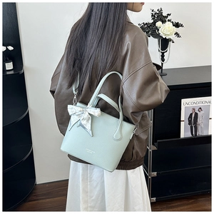 Détail du sac cabas en cuir vert menthe avec un foulard en soie à imprimé cœur au manche