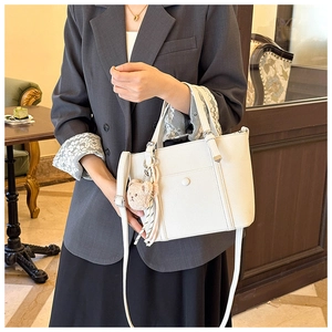 Détail du sac seau blanc en cuir grainé avec un adorable porte-clés ours marron