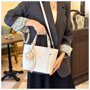 Sac à main beige minimaliste avec charm d'ours en peluche dans un cadre de café chic