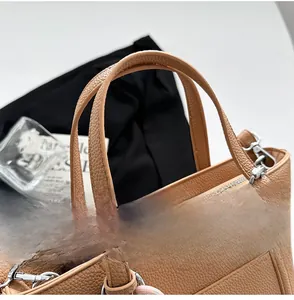 Détail macro de l'anse du sac en cuir grainé caramel avec boucle métallique argentée