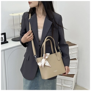 Détail du sac seau abricot en cuir grainé avec foulard à motifs cœurs et bandoulière réglable