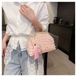 Close-up of pink satin shell bag with floral embroidery, pearls, and tassel details