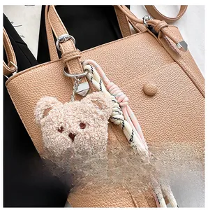 Détail d'un sac cabas en cuir grainé avec un charmant pendentif en forme d'ours en peluche